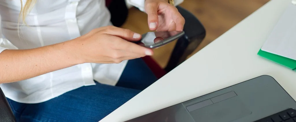 Profesional usando el móvil en el escritorio, microlearning accesible desde cualquier dispositivo