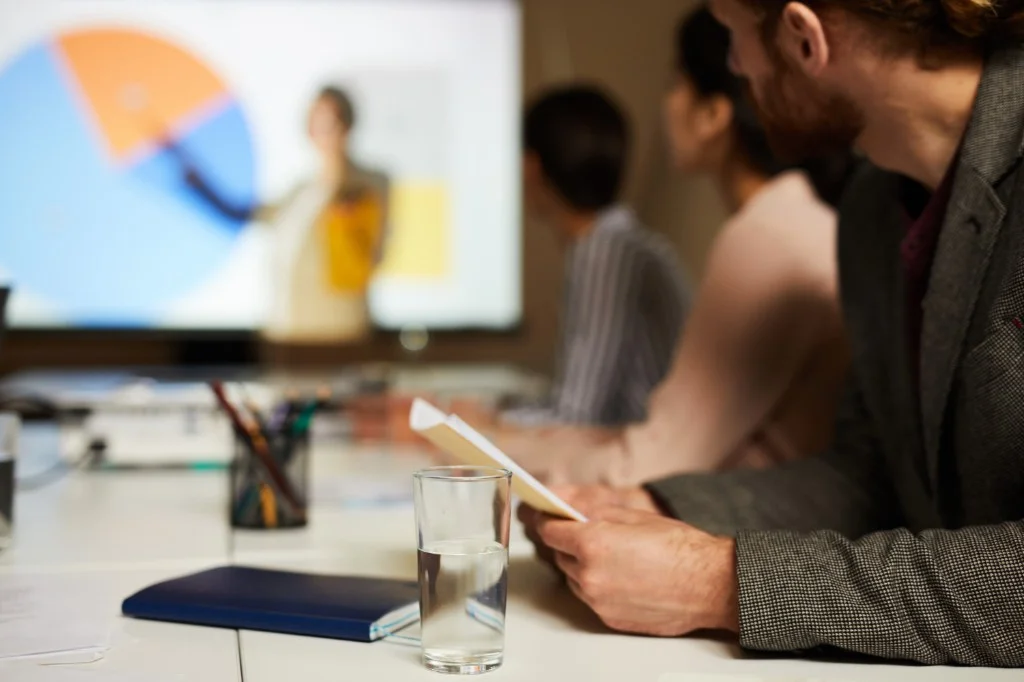 Participante en una sesión formativa revisando documentación, con presentación al fondo